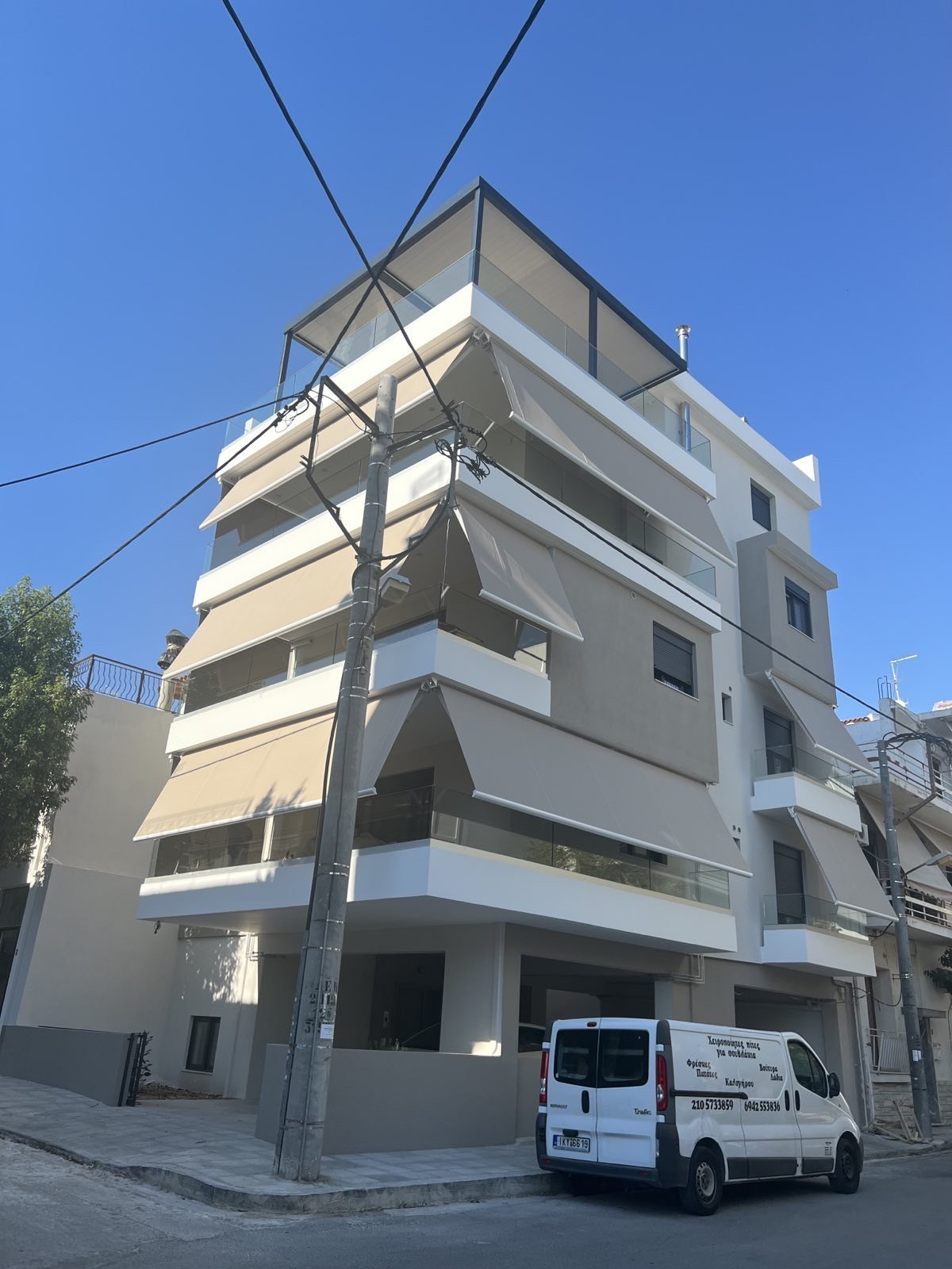 Πολυκατοικία με τέντες και το βαν της Pergotenta μπροστά