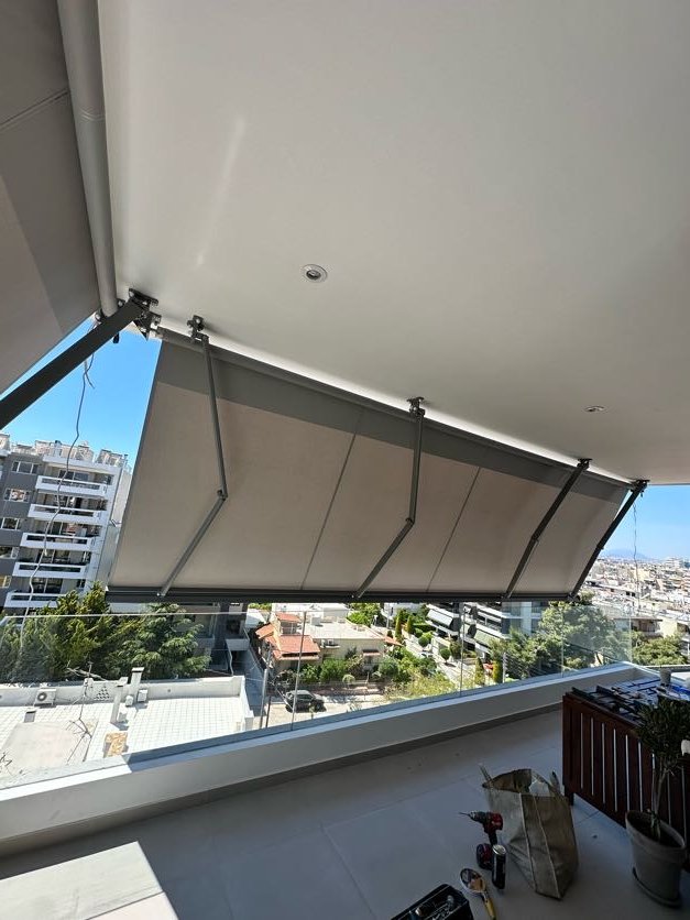 Γκρι κασετίνα τέντα σε μπαλκόνι ψηλού ορόφου με θέα στον Άλιμο, εγκατάσταση Pergotenta