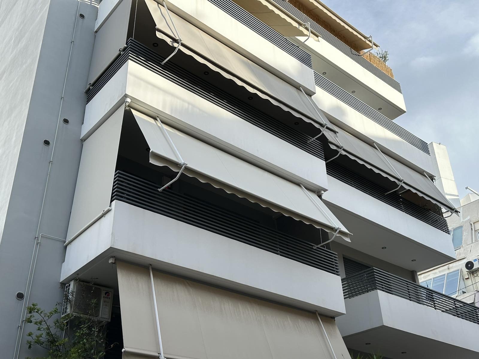 Τέντες με βραχίονες σε μπαλκόνια πολυκατοικίας με κεραμοσκεπή και δέντρα, Pergotenta